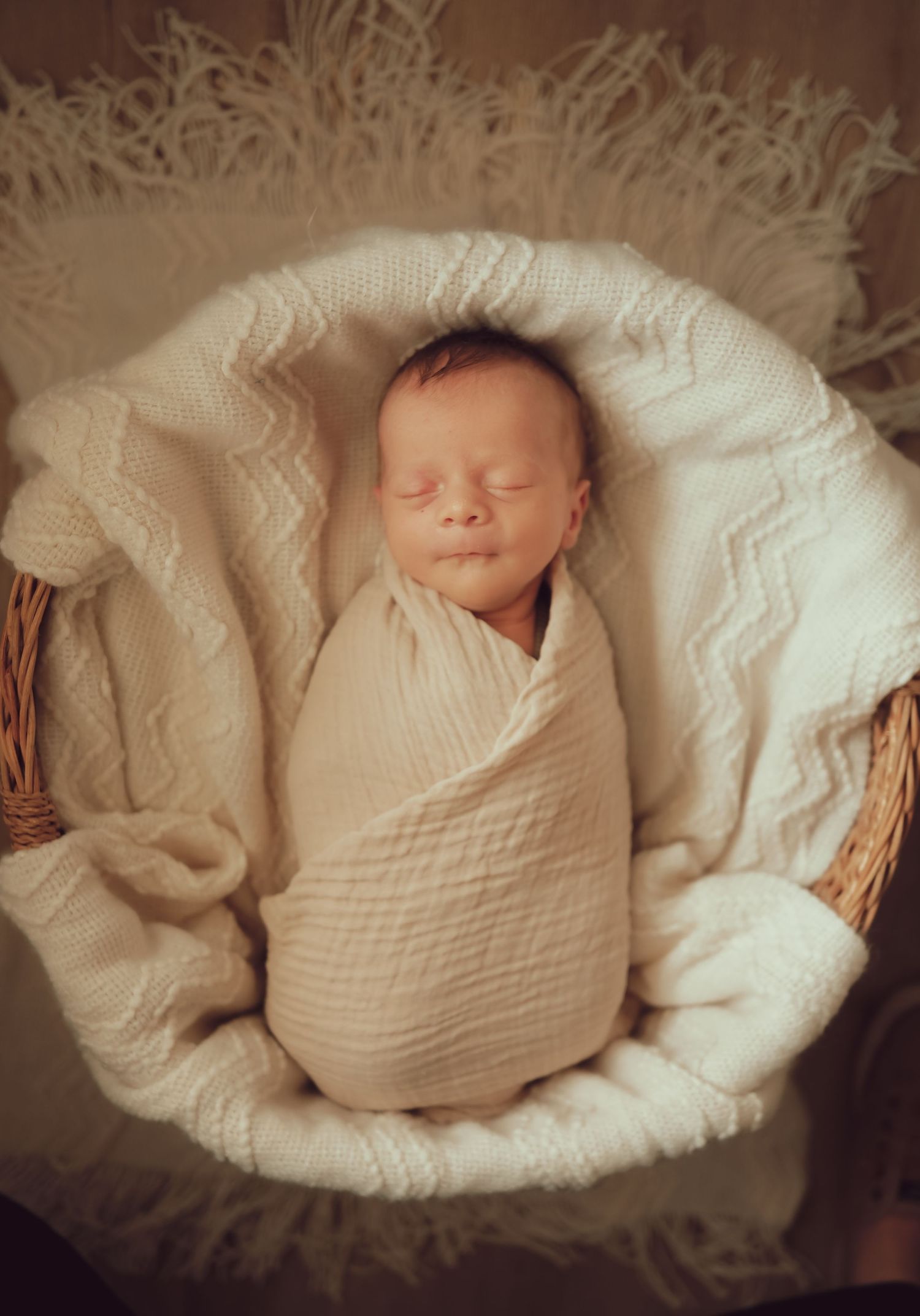 Newborn wrapped and sleeping in a soft basket