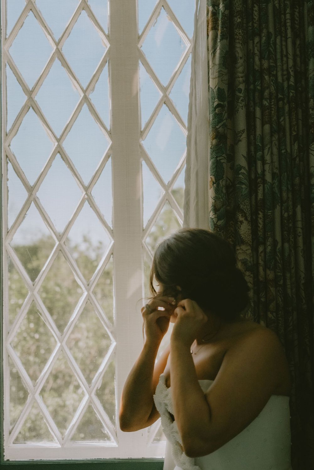 Bride getting ready beside a tall window before her Lafayette wedding