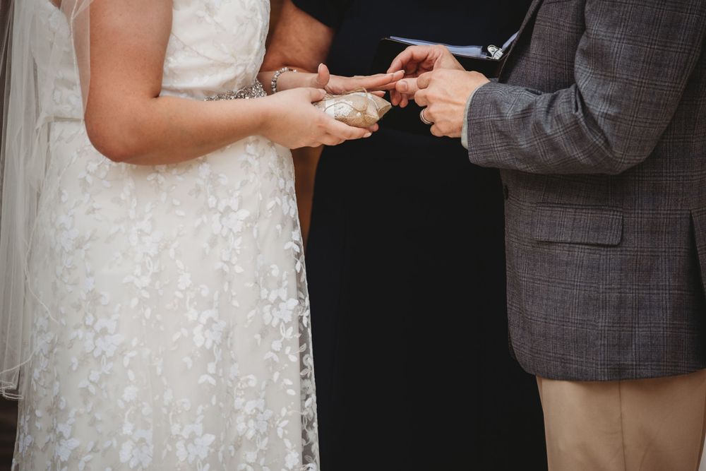Couple exchanging rings during an outdoor wedding ceremony