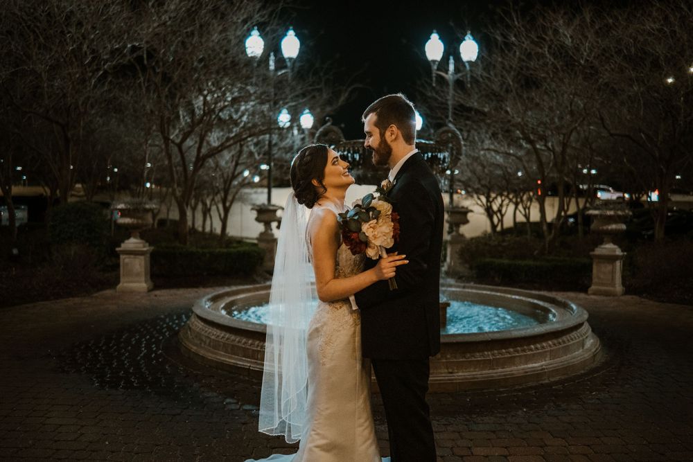Newlyweds photographed beside a softly lit fountain at night