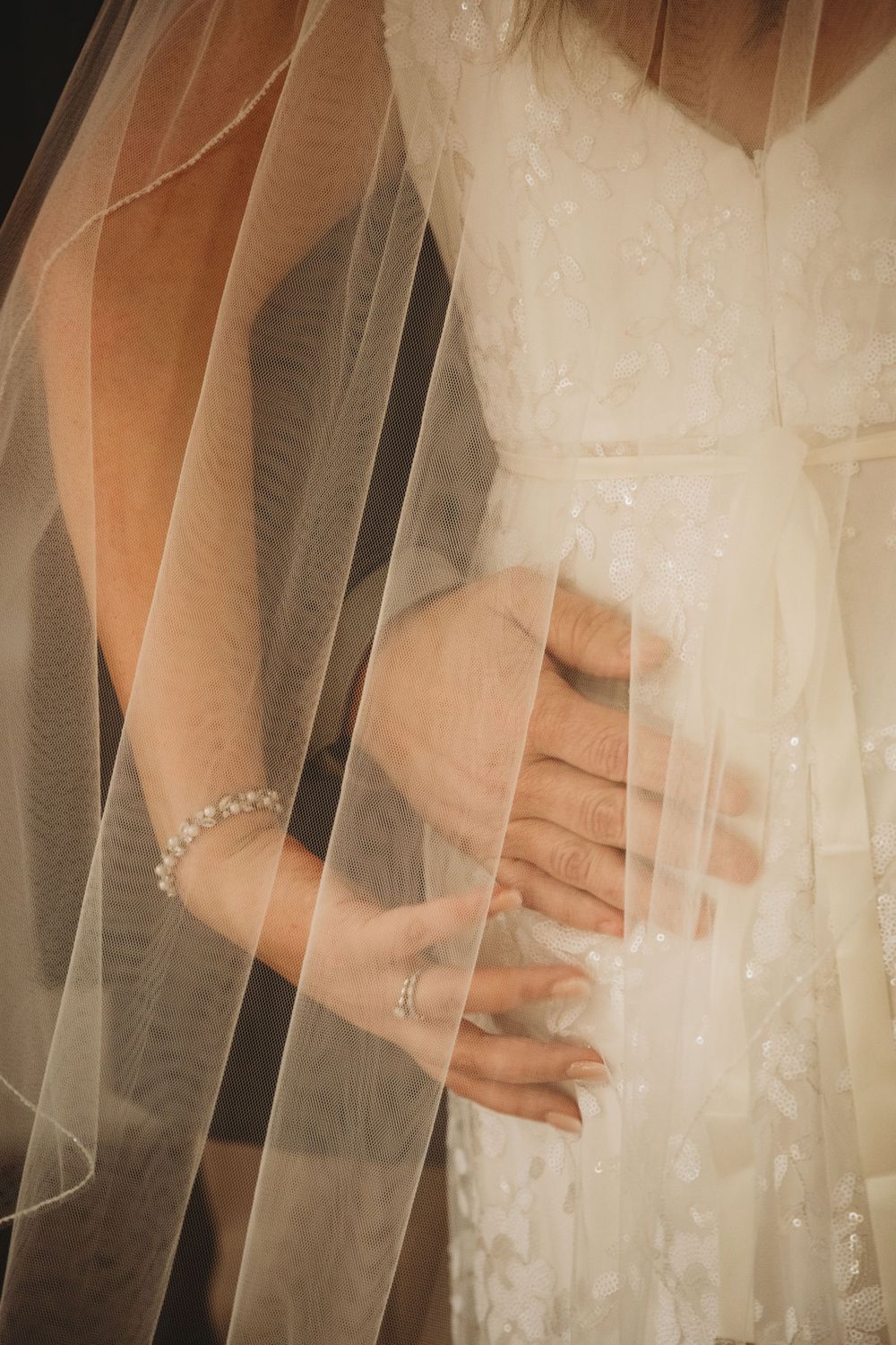 Bride and groom holding hands beneath the bride's veil