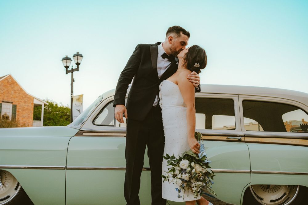 Newlyweds kissing beside a vintage car after their Lafayette wedding